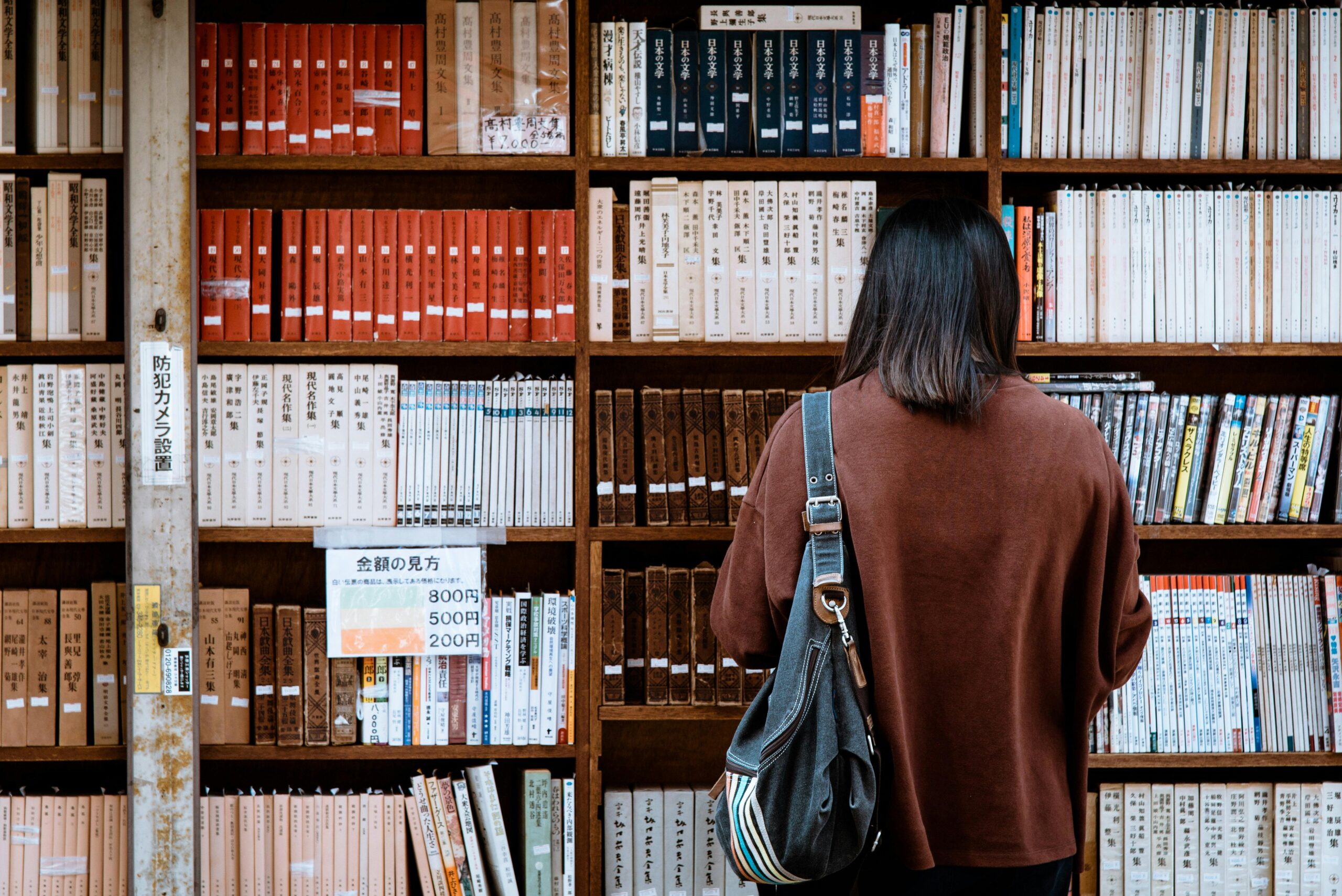 About Us 1 Woman browsing books at a library in Nagano, Japan. Explore knowledge and literature.